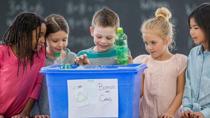 Kids around a blue recycling bin